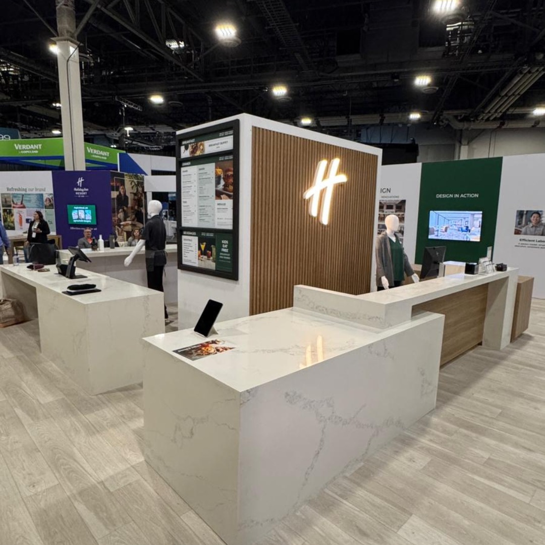Tradeshow booth featuring a custom quartz counter with a sleek, modern design, wood panel accents, and illuminated branding.