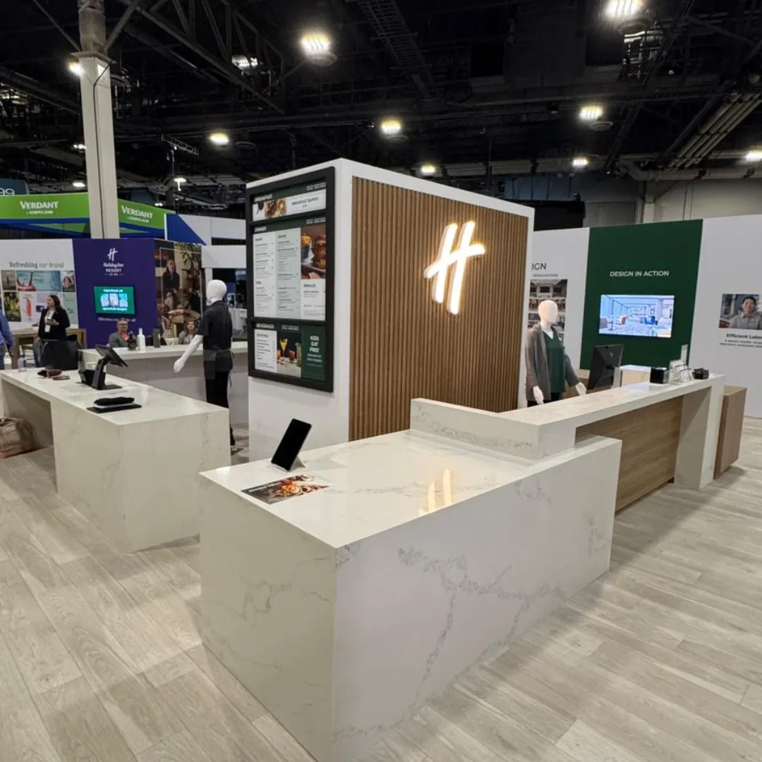 Modern trade show booth with quartz countertops and illuminated branding display, featuring sleek design.