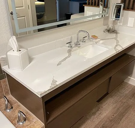 Custom stone vanity top with elegant white surface and subtle veining, paired with modern wooden cabinetry.